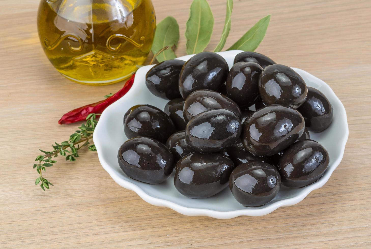 black-olives-on-the-plate-and-wooden-background-free-photo